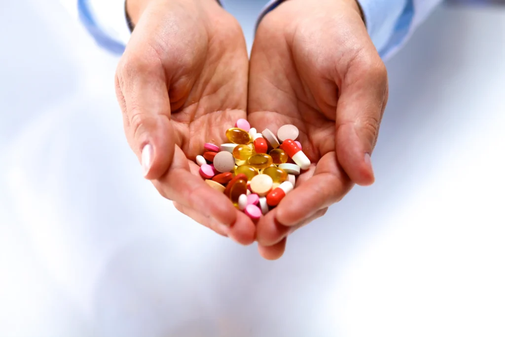 2 Hände bieten Medikamente in Form von Tabletten, Pillen und Kapsel an